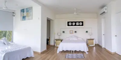 two beds in a room with white walls and wooden floors at Casa Romero Cartagena Casa de Playa in Cartagena de Indias