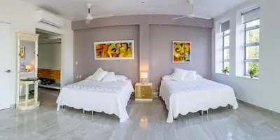 two beds in a room with two windows at Casa Romero Cartagena Casa de Playa in Cartagena de Indias
