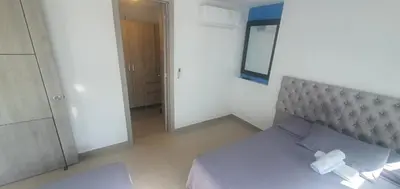 a white bedroom with a bed and a mirror at Lodging Palmetto apto 4 Bocagrande in Cartagena de Indias