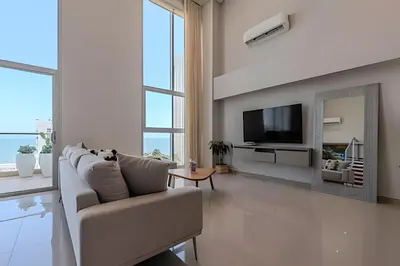 a white living room with a couch and a tv at Doble altura y lujoso apto vista al mar in Cartagena de Indias