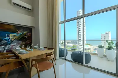 a dining room with a table and a large window at Doble altura y lujoso apto vista al mar in Cartagena de Indias