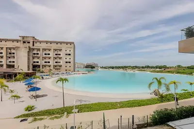 a large swimming pool with palm trees and a building at Espectacular vista a laguna de Kristal / 1 alcoba in Los Arrayanes