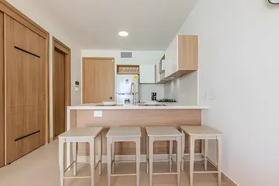 a kitchen with white countertops and stools at Espectacular vista a laguna de Kristal / 1 alcoba in Los Arrayanes