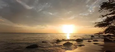 a sunset on a beach with rocks in the water at Apartamento Santa Marta Sector Don Jaca in Simón Bolivar