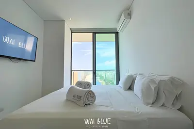 a white bedroom with a tv and a bed at Wai Blue/Luxury Beachfront/ Bello Horizonte/ TTO03 in Playa Dormida