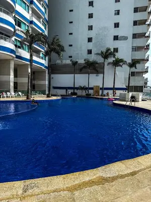 a large blue swimming pool in a building with palm trees at Piso 30 vista al mar, Palmetto 1 Bocagrande in Cartagena de Indias