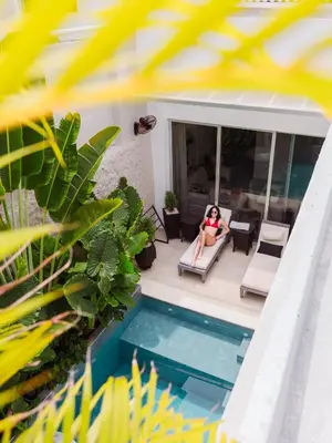a woman sitting on a chair next to a swimming pool at The Villa Catalina in Cartagena de Indias