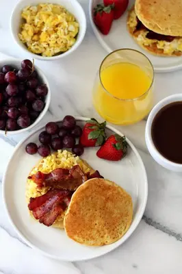 a table with plates of breakfast food with pancakes and strawberries at The Villa Catalina in Cartagena de Indias