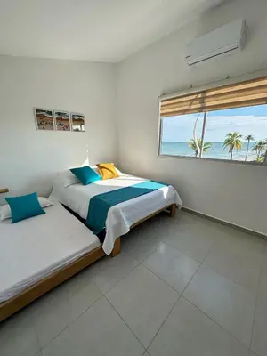 two beds in a bedroom with a view of the ocean at 302 Apartamento frente al mar in San Bernardo del Viento