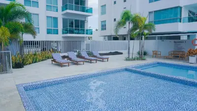 a swimming pool with lounge chairs next to a building at Magico Apartamento Frente al Mar 4 Habitaciones BM33 in Coveñitas