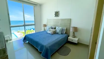 a bedroom with a bed and a view of the ocean at Magico Apartamento Frente al Mar 4 Habitaciones BM33 in Coveñitas