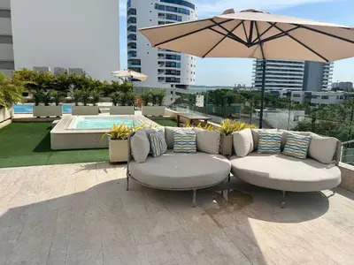 a patio with two chairs and an umbrella and a pool at Suite con vista al mar Cartagena CB808 in Cartagena de Indias