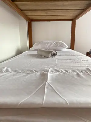 a white bed with a pillow and a bag on it at Amplio y Luminoso Apto en Tolú in Santiago
