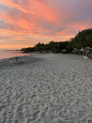 two people sitting on a beach at sunset at VILLA LILI Santa Marina Santa Marta in Santa Marta