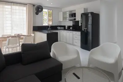 a kitchen with a black refrigerator and white chairs at edificio Alba in Cartagena de Indias