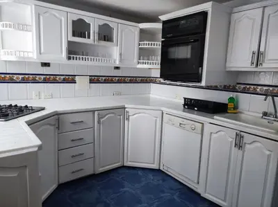 a white kitchen with white cabinets and black appliances at Cartagena Beach con vista al mar in Cartagena de Indias