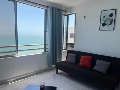 a living room with a black couch and large windows at Mar del norte in Cartagena de Indias