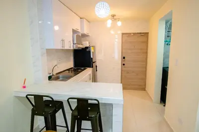 a kitchen with a white counter and two black chairs at 2 double beds 2001 in Cartagena de Indias