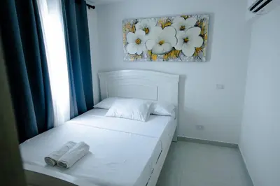 a white bed in a room with a picture on the wall at Apartamento Cartagena Playa 2203 in Cartagena de Indias