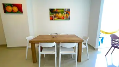a dining room table with white chairs and a painting at Magico Apartamento Frente al Mar 3 Habitaciones AR42 in Coveñas