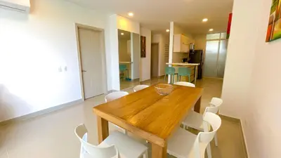 a dining room with a wooden table and white chairs at Magico Apartamento Frente al Mar 3 Habitaciones AR42 in Coveñas