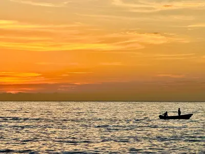 two people in a boat on the water at sunset at Hermoso apartamento con vista al mar in Santa Marta
