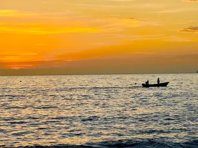 two people in a boat in the ocean at sunset at Hermoso apartamento con vista al mar in Santa Marta