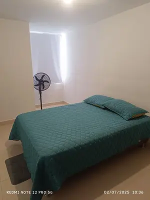 a bedroom with a bed with a green comforter and a fan at Lajoya in Barranquilla