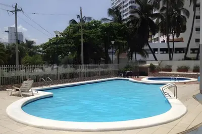 a large swimming pool with two chairs and aermottermott at Hermoso apartamento con vista en el laguito in Cartagena de Indias