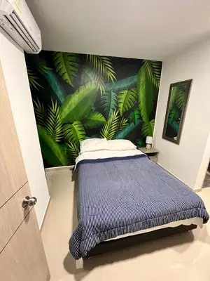 a bedroom with a blue bed with a mural of leaves at Live in the Heights Fresh and Bright Apartment in Cartagena de Indias