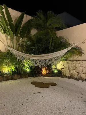 a hammock in a garden with palm trees and lights at Villa Privada con Piscina - Playas del Atlantico in Tubará