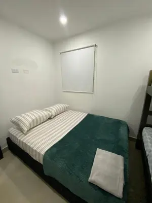 a white bedroom with a bed with a green blanket at Apartamento para Grupos En La Boquilla BBB in Cartagena de Indias