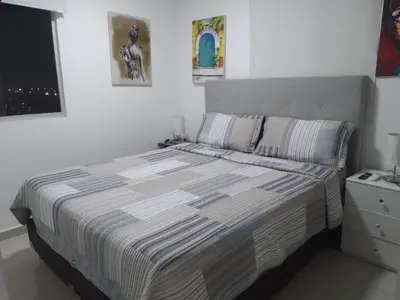a bedroom with a bed with a striped comforter at VISTA CARIBE- apartamento piso 25, marbella in Cartagena de Indias