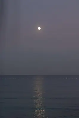a moon rising over the ocean with the water at CARDUMEN Arte y Cocina in Playa Blanca