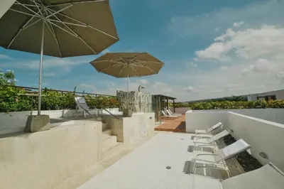 a patio with chairs and an umbrella on a roof at Incredible 2BR with AC in Ciudad Amurallada in Cartagena de Indias