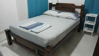 a bed with a wooden frame with two pillows on it at Hospedaje MangleRojo - Cerca al Mar in Coveñas