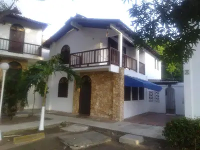 a white house with a balcony and a palm tree at Victoria Real in Coveñas