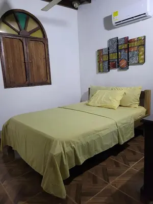 a bedroom with a bed with a green blanket on it at Victoria Real in Coveñas