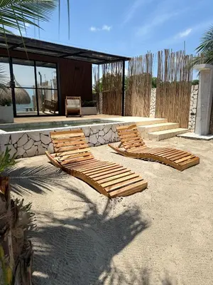 a group of wooden lounge chairs sitting in the sand at Luxury Suite frente de Mar Piscina Restaurante y Bar in San Silvestre