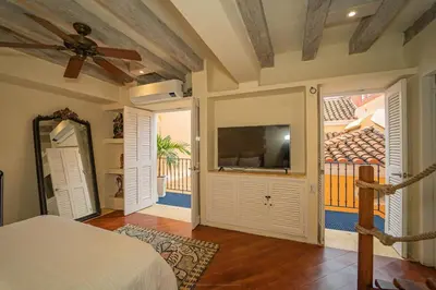a bedroom with a bed and a television and a balcony at Niña Maria pool House Plaza San Diego, Downtown! in Cartagena de Indias