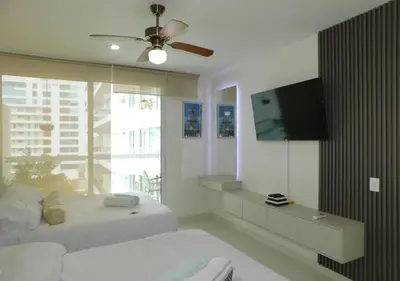 a bedroom with two beds and a flat screen tv at Apartamento Morros 3 Cartagena, Piscina Playa y Mar in Cartagena de Indias