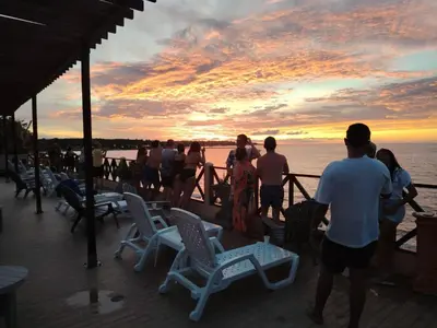 a group of people standing on a deck watching the sunset at Dorado Beach Isla in Playa Punta Arena