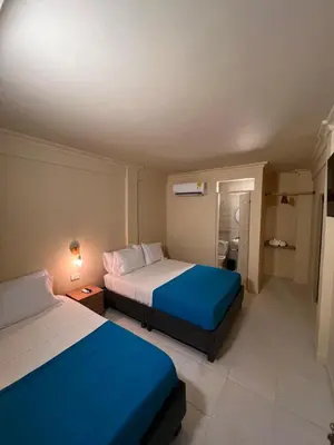 two beds in a small room with blue sheets at Alma Del Mar in Cartagena de Indias