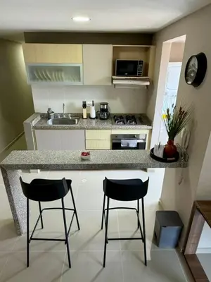 a kitchen with two bar stools and a counter top at Apto Moderno Cómodo y acogedor Excelente ubicación Norte Barranquilla in Barranquilla