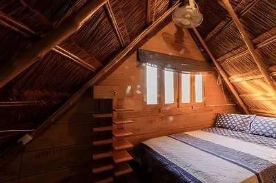 a attic room with a bed and a window at Tita Tati Disconnect near Cartagena in Punta Canoas