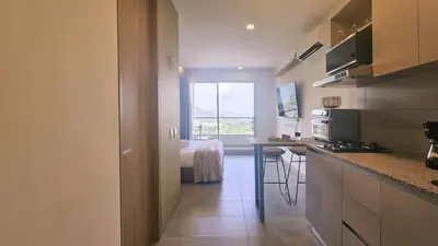 a kitchen with a table and a room with a bed at Caribbean Refuge - Beach and Pool Access 10th Floor in Santa Marta