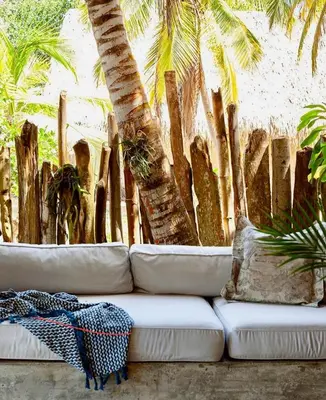 a white couch sitting next to a bunch of palm trees at En La Casa Del Mar in Moñitos