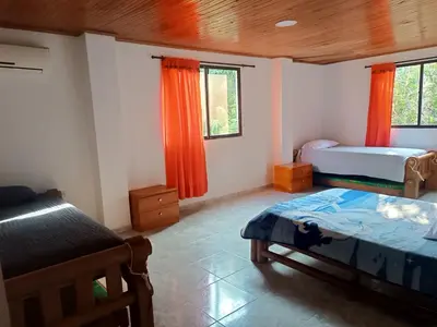 a bedroom with two beds and orange curtains at La Trinidad in Santa Veronica