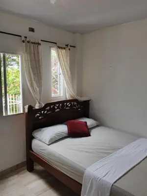 a bedroom with a bed and two windows at Kasa Soffi in Moñitos