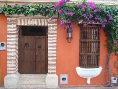 an orange building with a door with flowers on it at Luxury Colonial Villa Old City Cartagena Rooftop Views Private Pool in Cartagena de Indias